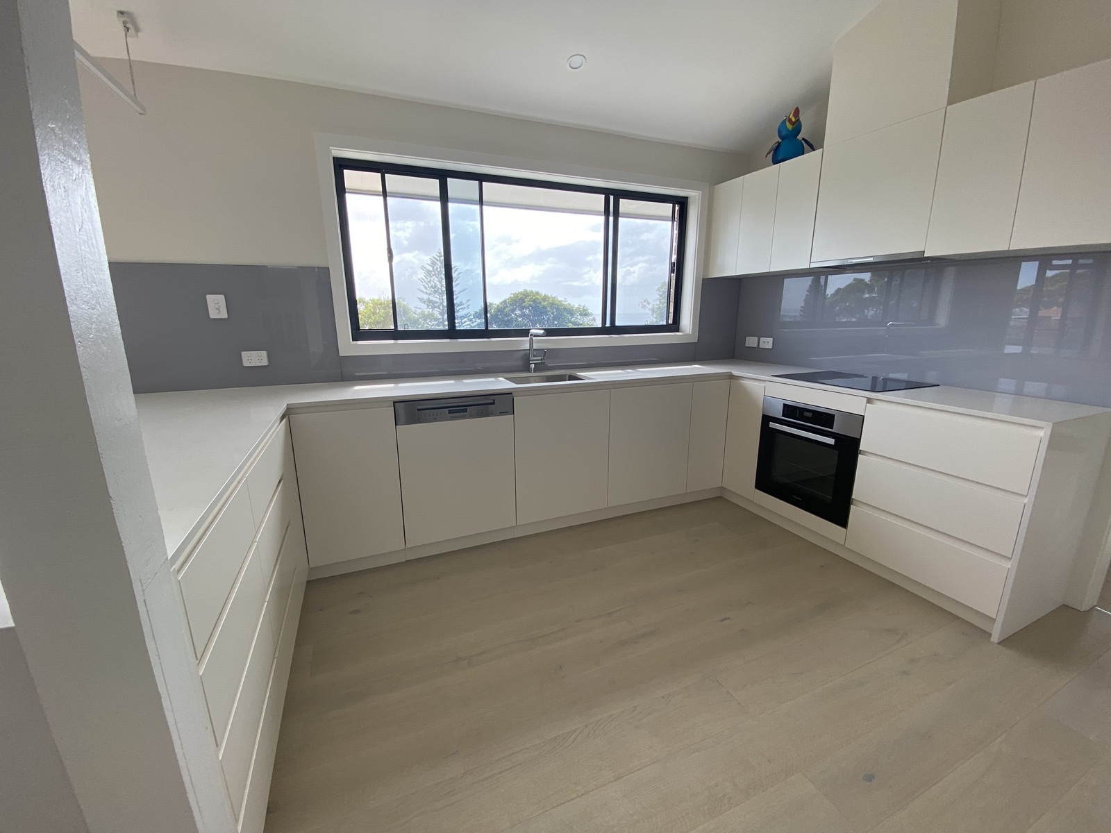 Completed kitchen renovation with white cabinetry and stone benchtops